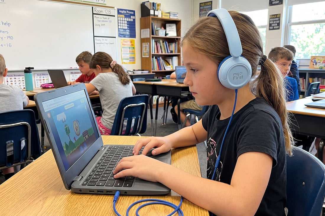 A young girl wearing blue headphones in a classroom.